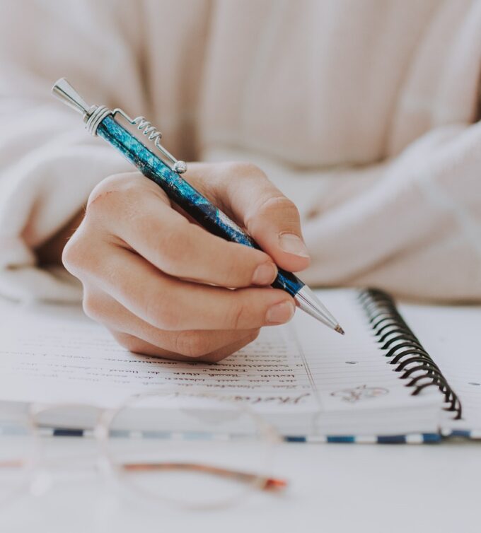 Image of someone writing with a pen